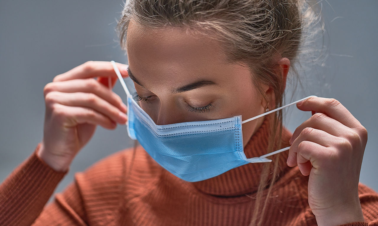 Healthy woman putting on medical protective mask to health protection and prevention during flu virus outbreak, epidemic and infectious diseases